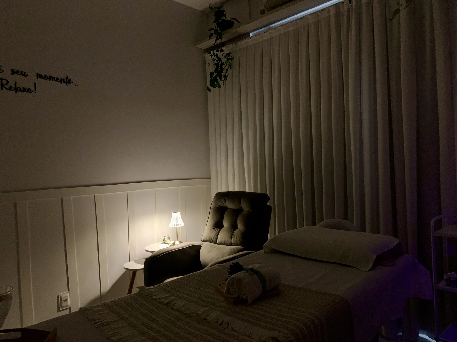 Espaço de atendimento com maca, poltrona e iluminação acolhedora